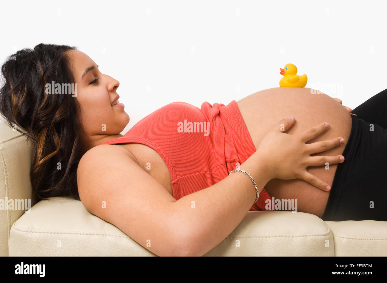Pregnant woman lying down with a rubber duck on her belly Stock Photo