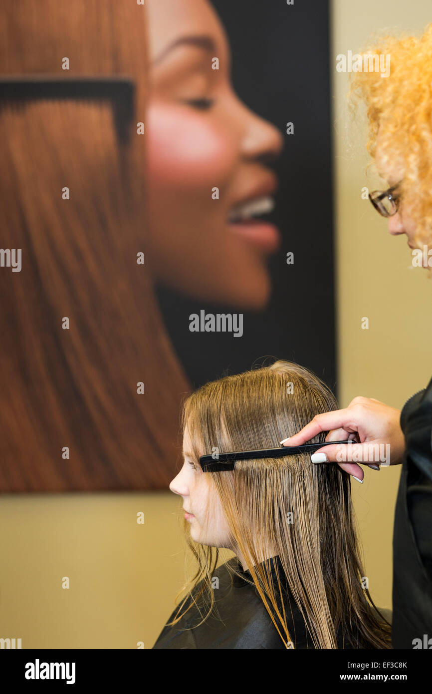 Caucasian girl getting her hair cut and styled by a mixed race beautician in a salon Stock Photo