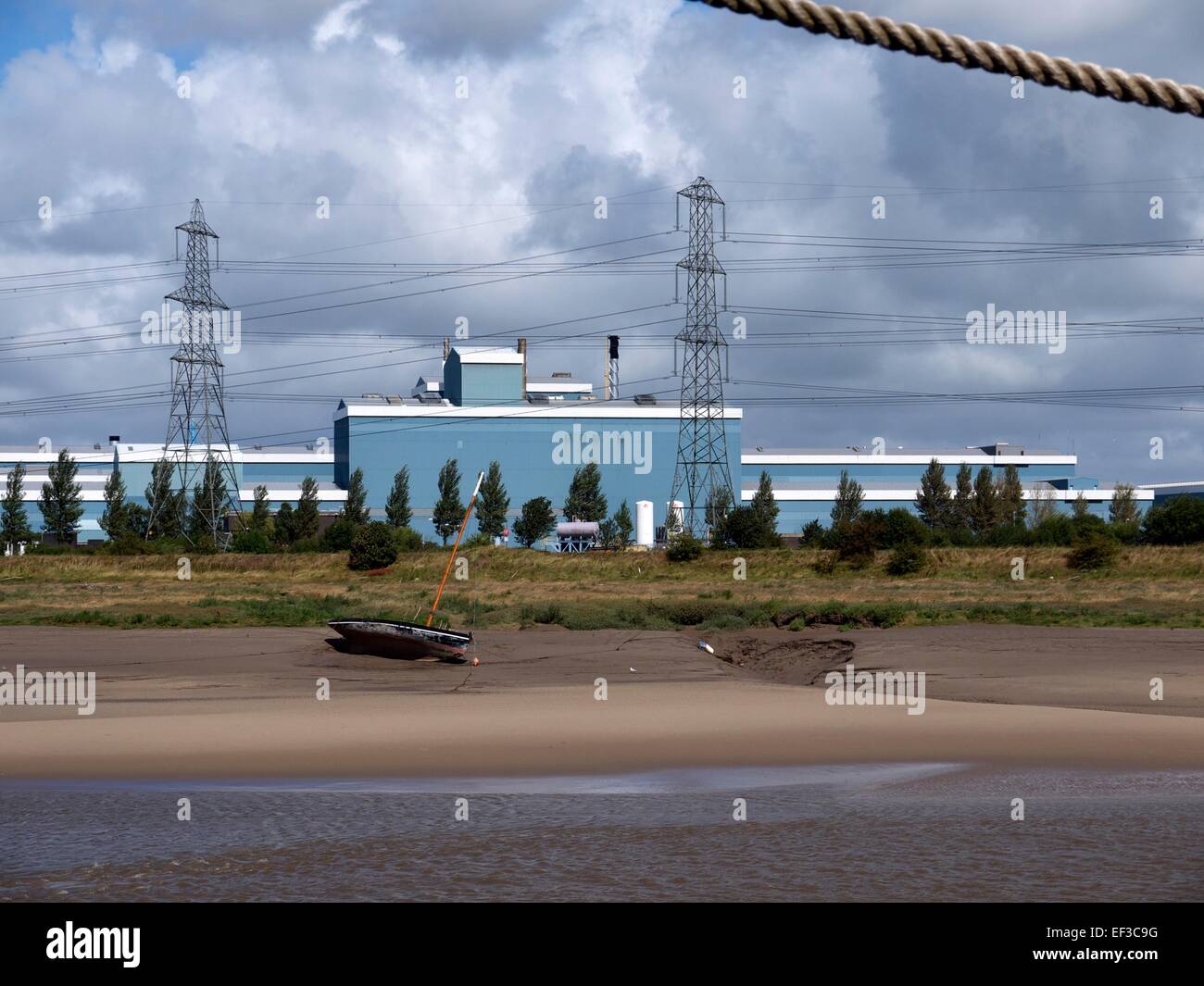 Factory on the banks of the Dee Estuary and a boat sitting on the sand Stock Photo