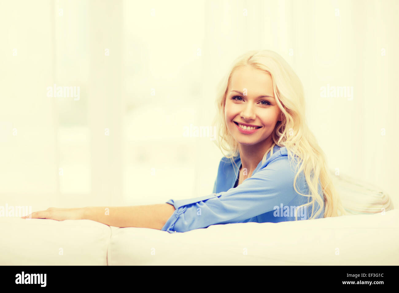 smiling young woman lying on sofa at home Stock Photo - Alamy