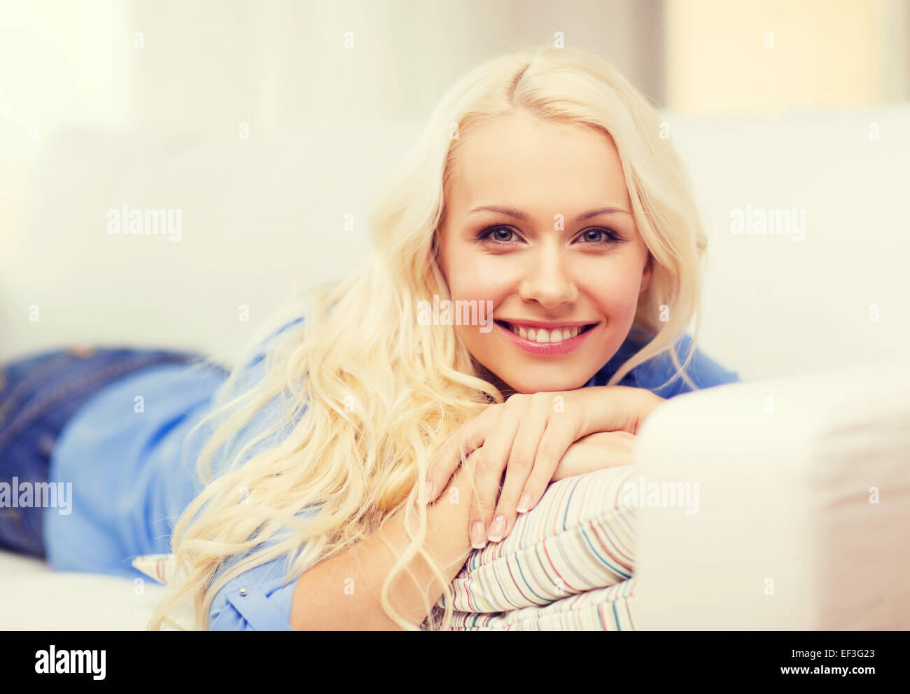 smiling young woman lying on sofa at home Stock Photo - Alamy