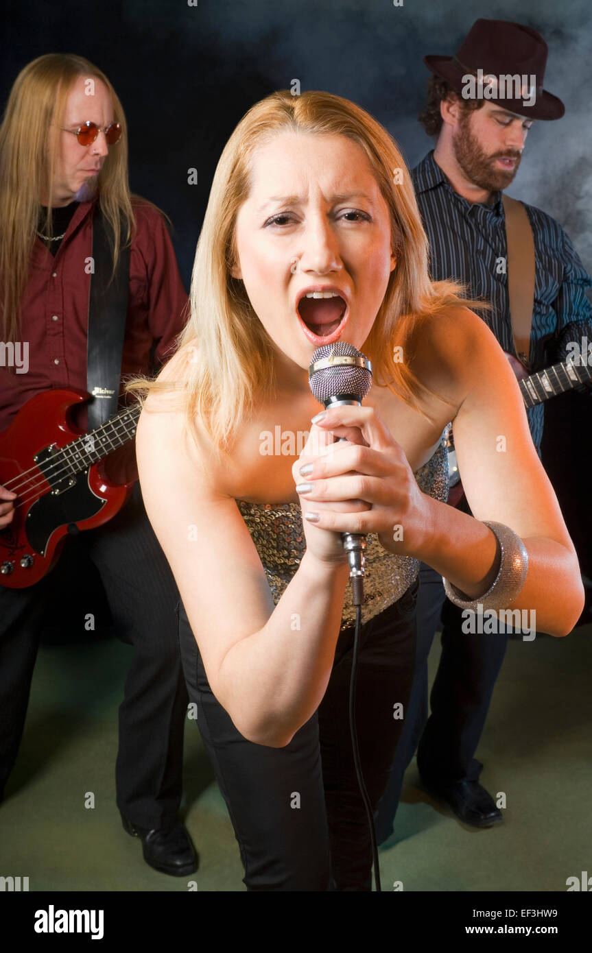 Woman singing with two guitar players Stock Photo