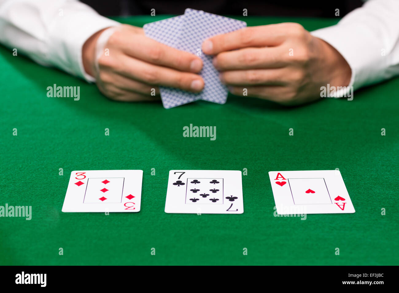 poker player holding playing cards at casino table Stock Photo