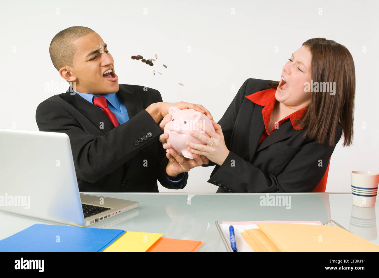 Colleagues fighting over a piggy bank Stock Photo