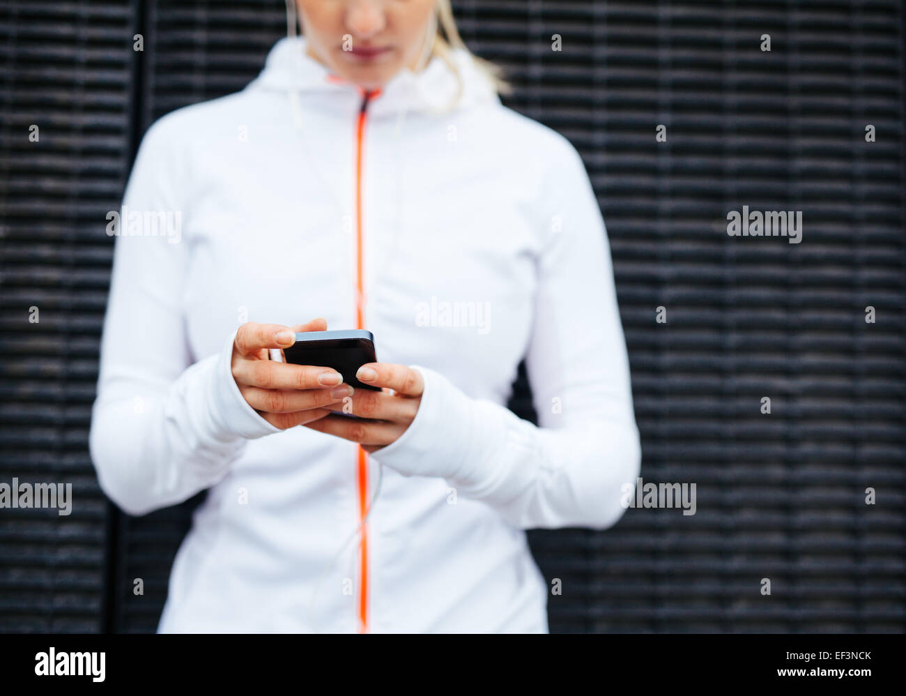 Cropped image of woman in sportswear using mobile phone. Focus on hands and smart phone. Stock Photo