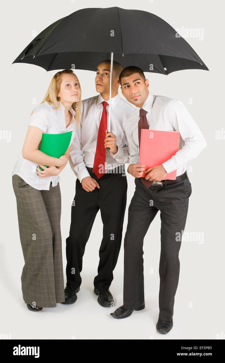 Colleagues standing under umbrella Stock Photo