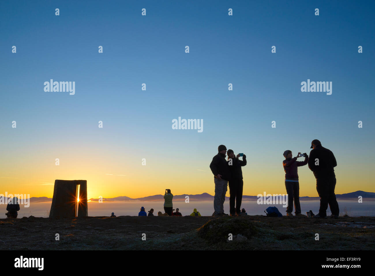 Sunrise at Mount Pisgah summit on January 1st, with people taking selfies at the Jed Kesey memorial sculpture, Lane County, Oregon Stock Photo