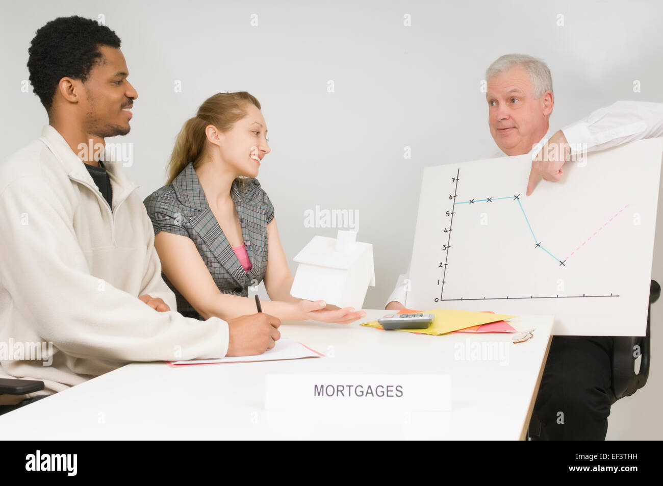 Mortgage broker sitting with clients Stock Photo