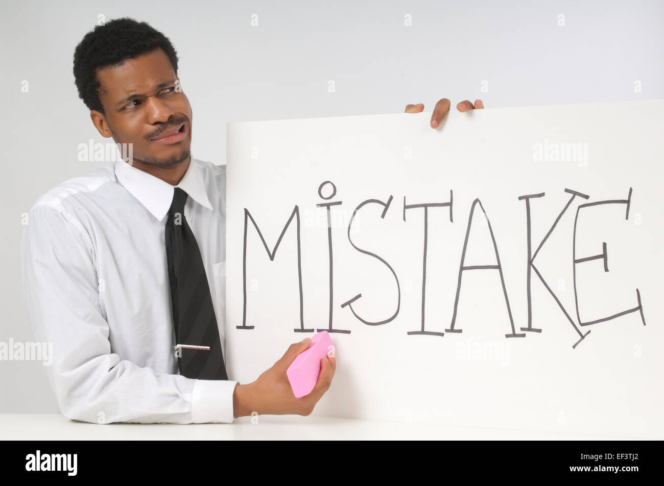 Perplexed businessman holding a sign that says mistake Stock Photo
