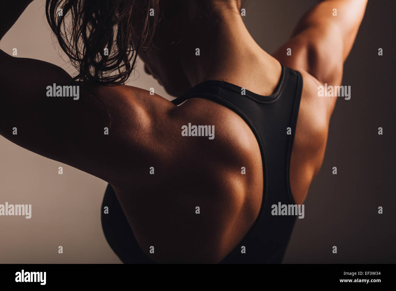 Close-up shot of back of female fitness model. Young woman in sports wear with muscular body. Stock Photo