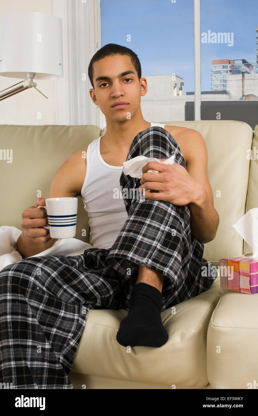Man with a cold sitting on couch Stock Photo