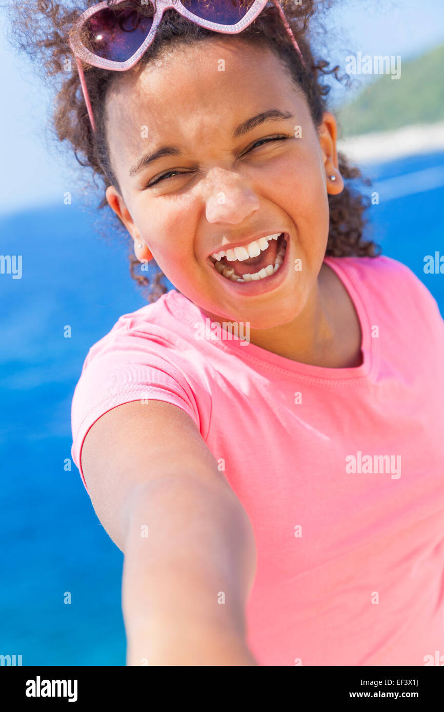 Selfie photograph of laughing happy mixed race African American female girl child wearing sunglasses on vacation Stock Photo