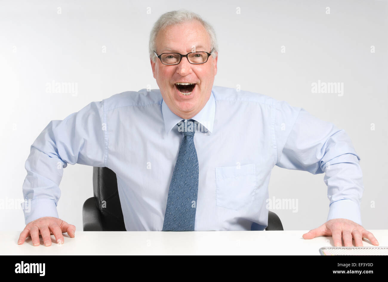 Happy businessman sitting at desk Stock Photo