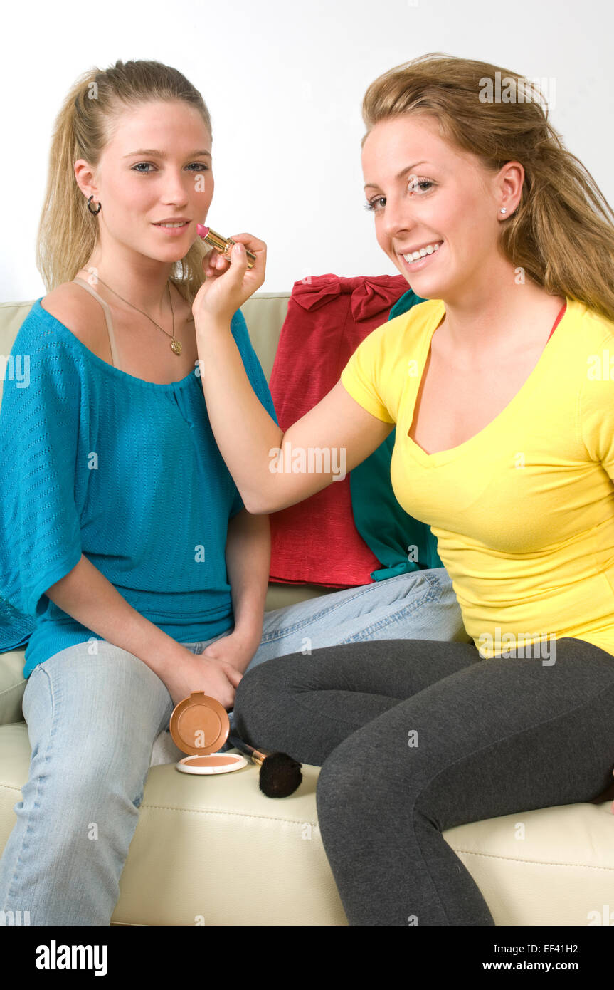 Woman putting lipstick on her friend Stock Photo