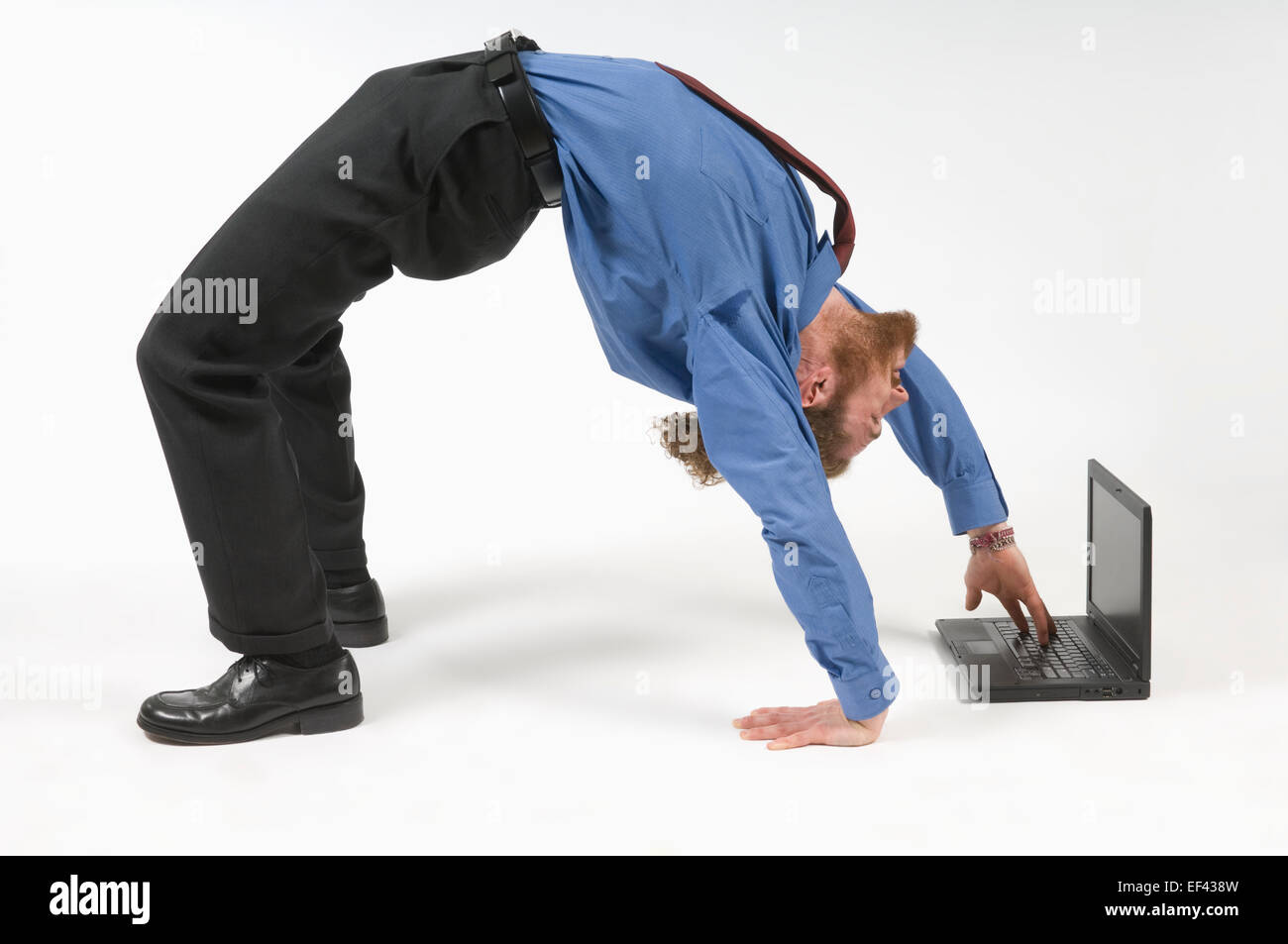 Businessman typing while bent over backwards Stock Photo
