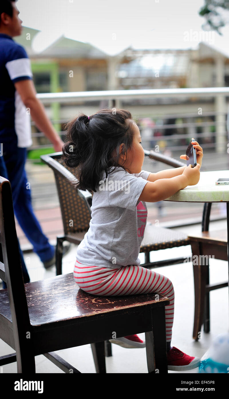 Korean Toddler using Cellphone Ayala Center Cebu City Philippines Stock Photo