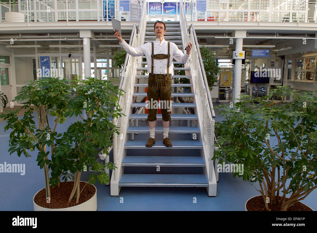 Consulate Munich Vice Consul Douglas Rose - dressed in traditional lederhosen - welcomes members of the traveling party for U.S. Secretary of State John Kerry to Munich, Germany, on January 10, 2015, as they wait in an airport lounge as he attends a meeting with Sultan Qaboos al-Said amid his trip to Ahmedabad, India, for the Vibrant Gujarat Summit. Stock Photo