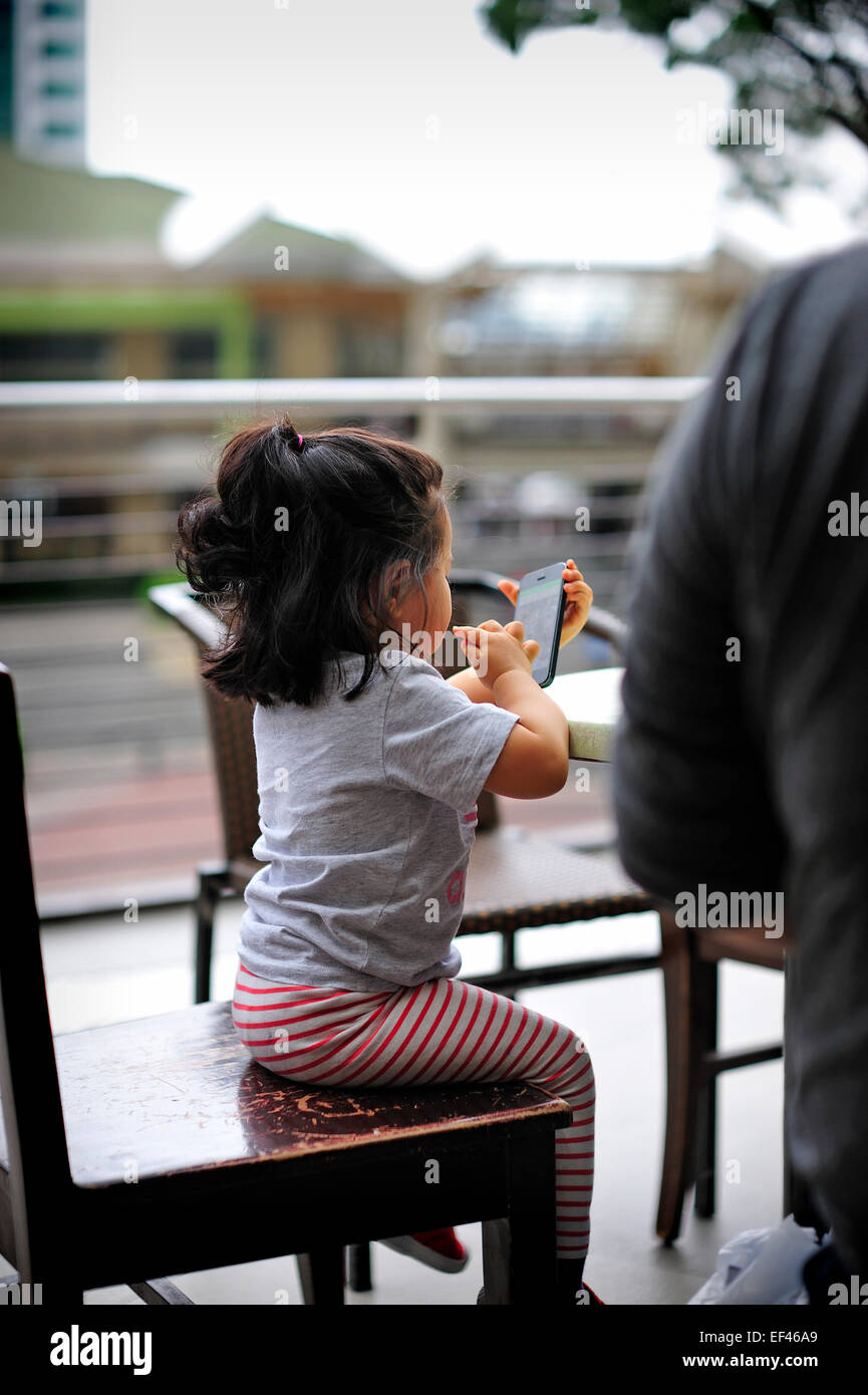 Korean Toddler using Cellphone Ayala Center Cebu City Philippines Stock Photo