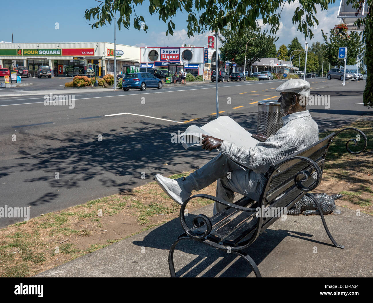 Barry - statue of a Kiwi bloke sitting reading a newspaper on a bench, main road katitkati town, Bay of Plenty New Zealand Stock Photo