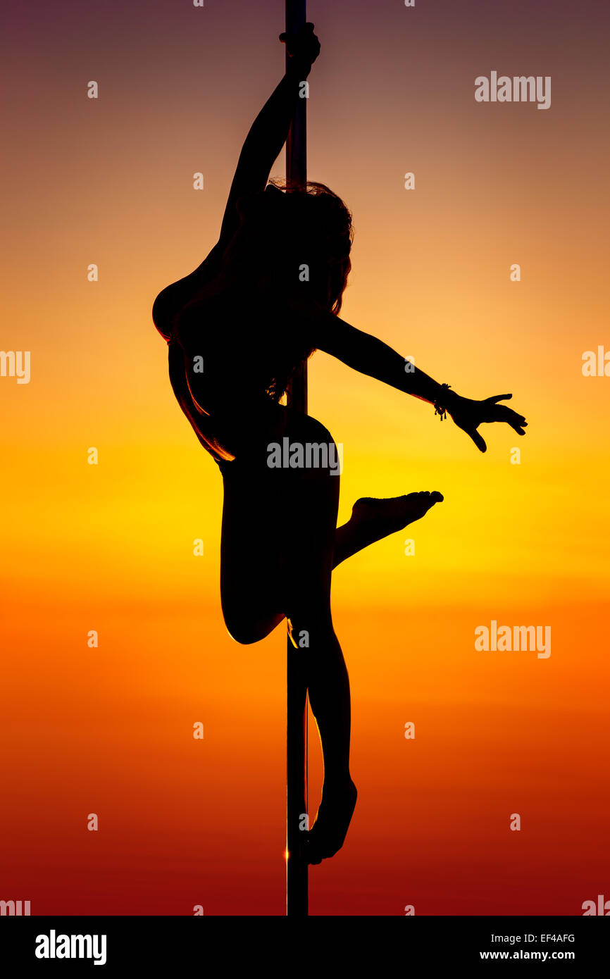 Young pole dance woman silhouette on sunset background. Stock Photo
