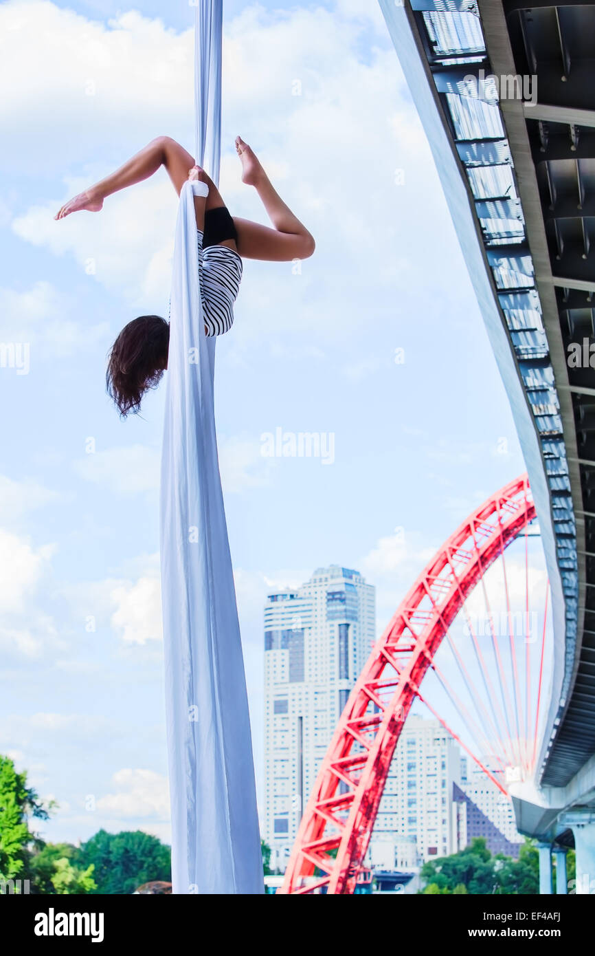 Young woman gymnast. On city and sky background. Stock Photo