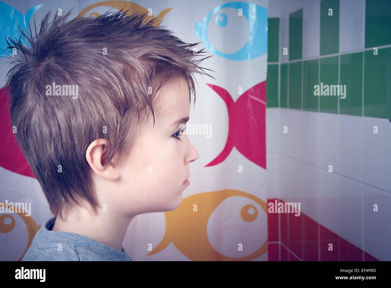 Young boy in bathroom looking at wall. Stock Photo