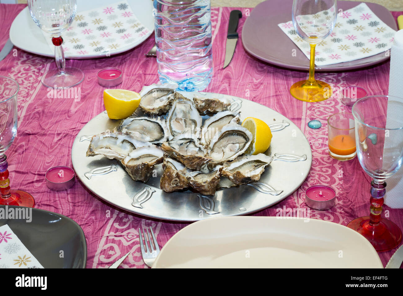 Oysters and lemon wedges on a set table. Stock Photo