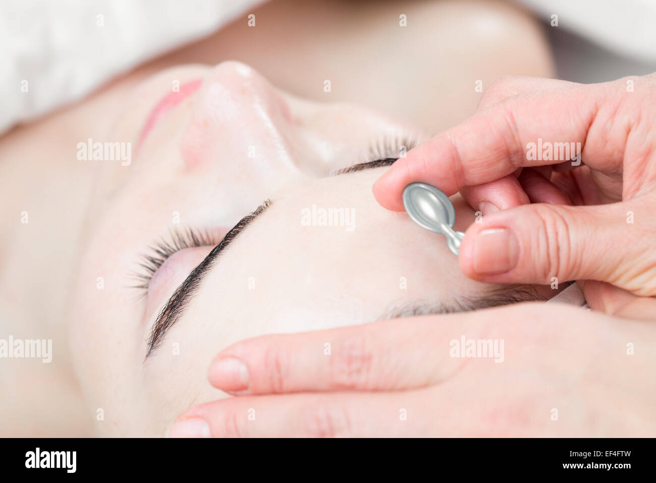 Serum capsule in front of young woman face in spa salon Stock Photo