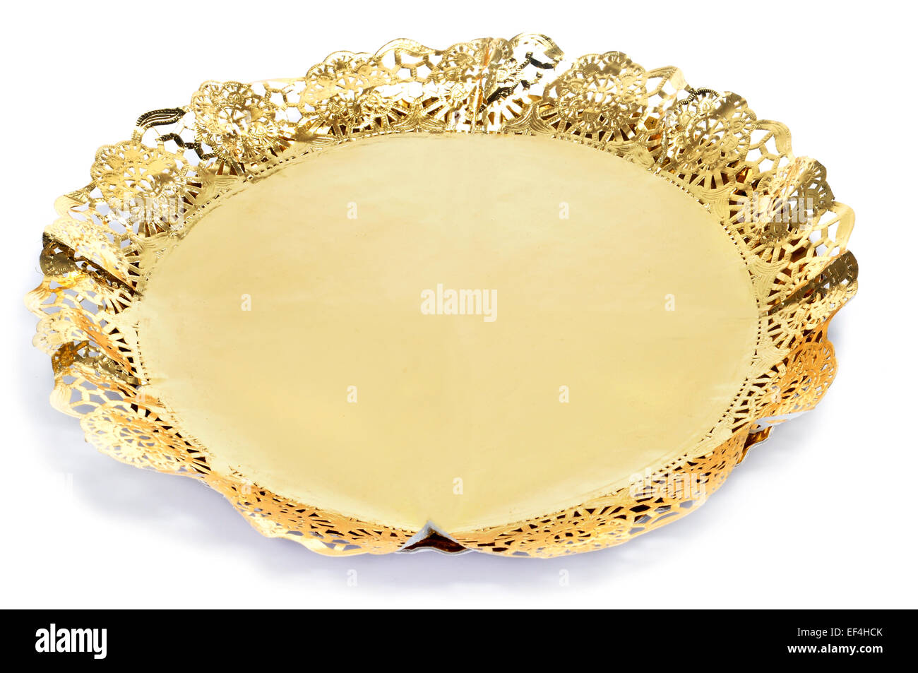 a golden paper lace doily on a cake board for display cakes on a white background Stock Photo