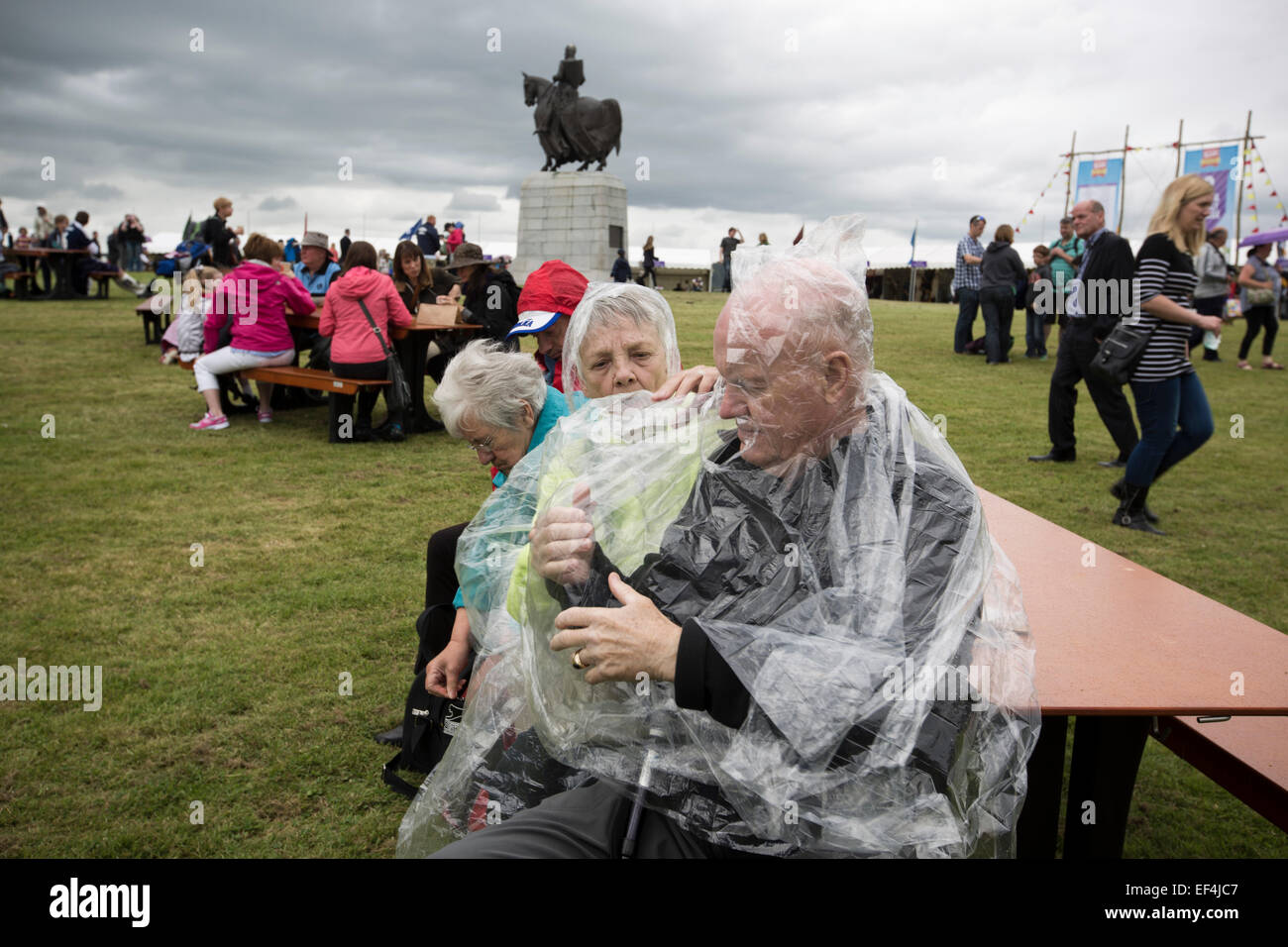 An elderly man putting on a rain poncho during events at Bannockburn Live, at Bannockburn, Stirlingshire. Stock Photo
