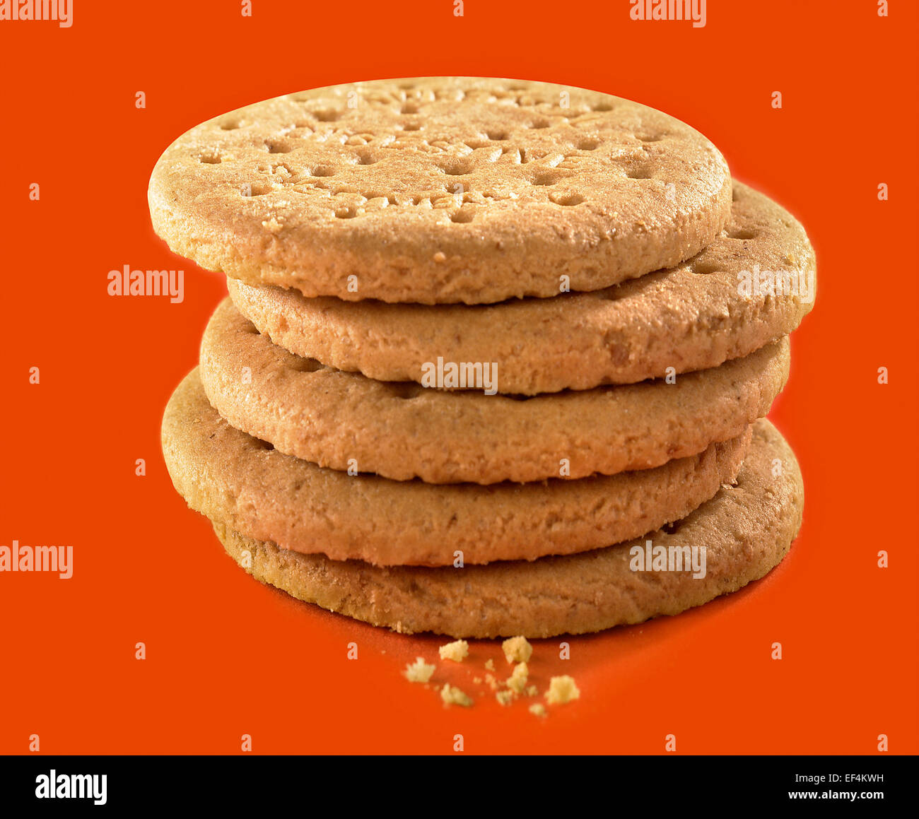 A stack of digestive biscuits with a few crumbs at the front Stock
