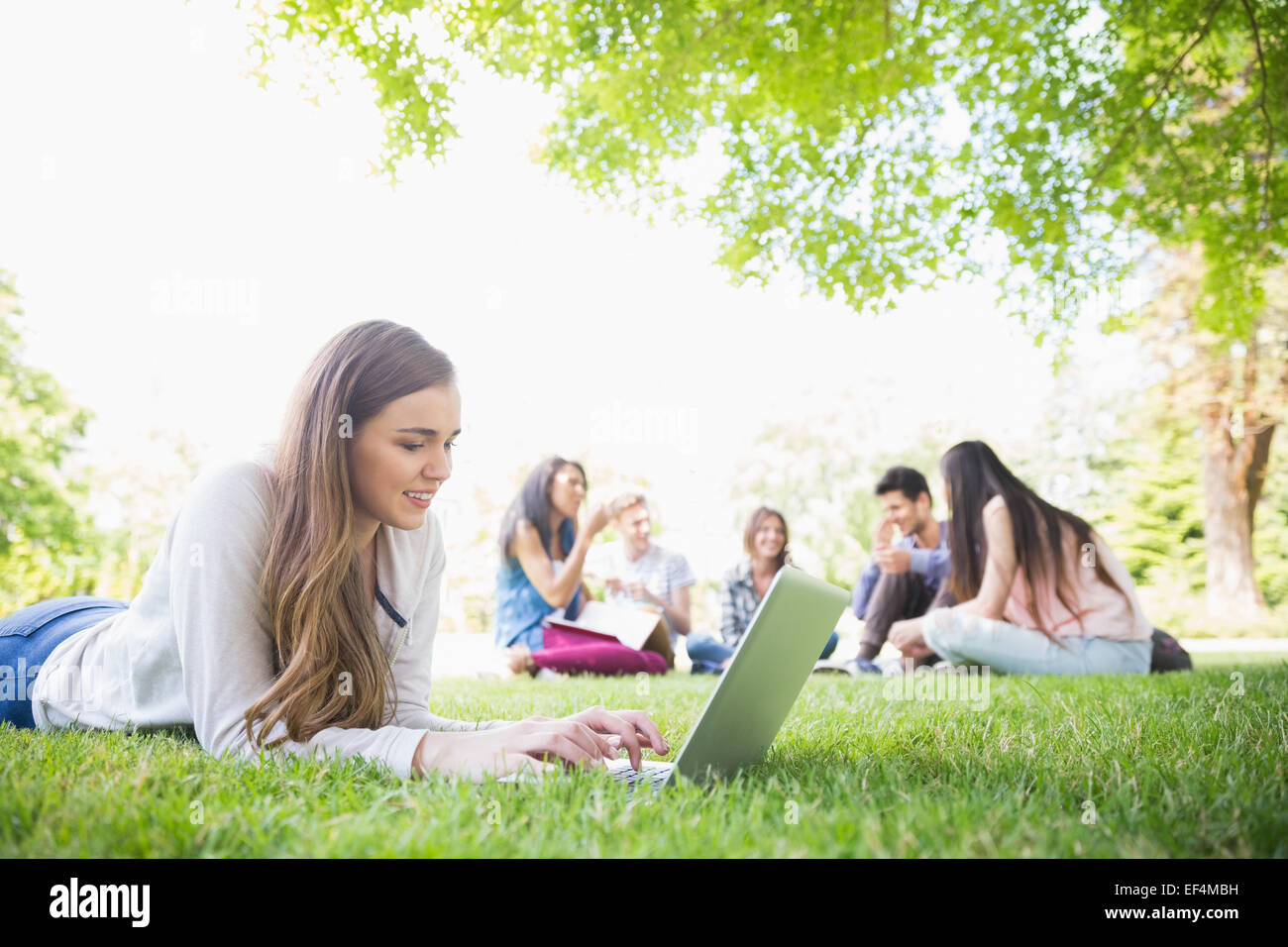 Happy student using her laptop outside Stock Photo - Alamy
