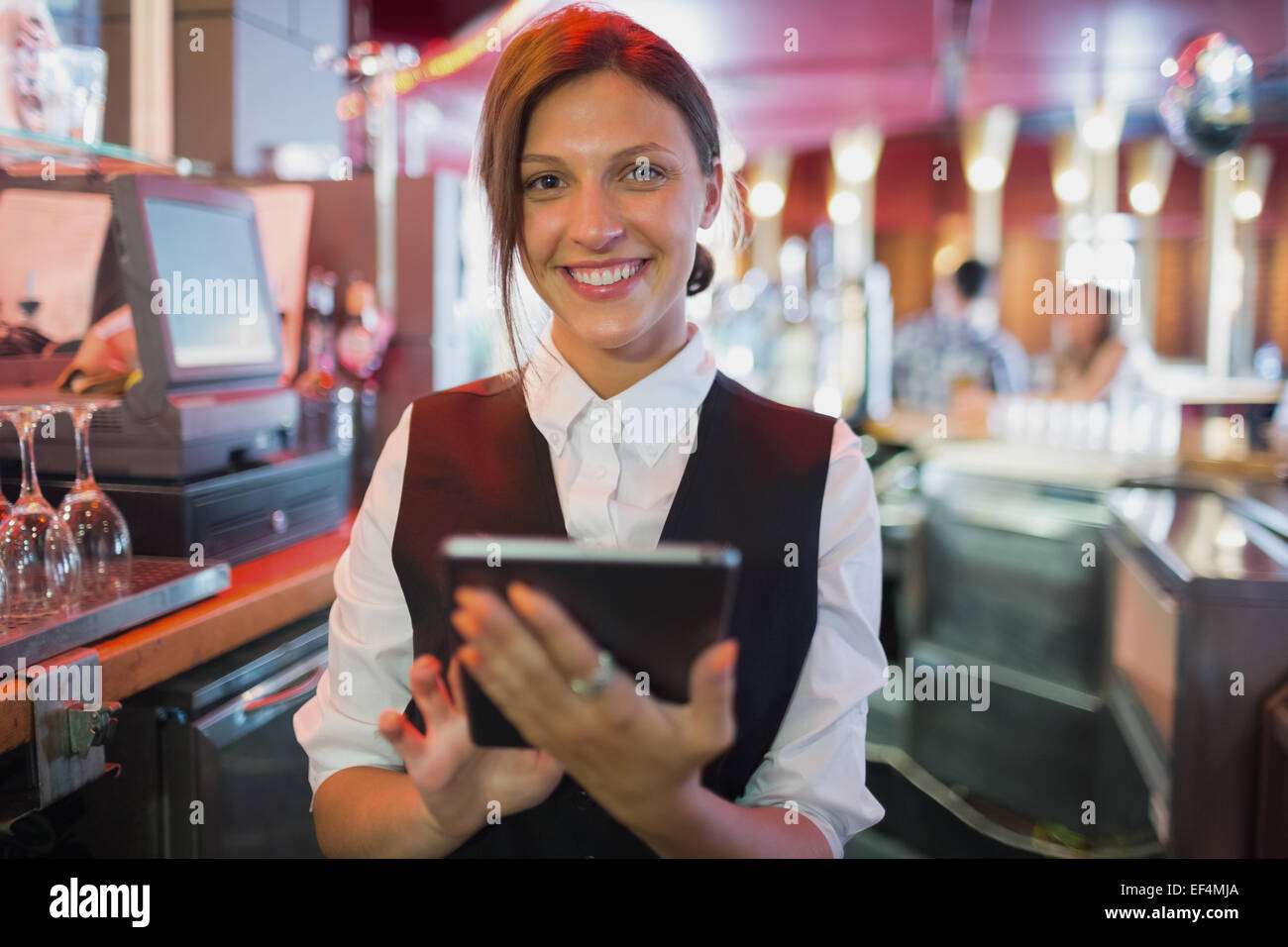 Focused barmaid using touchscreen till Stock Photo
