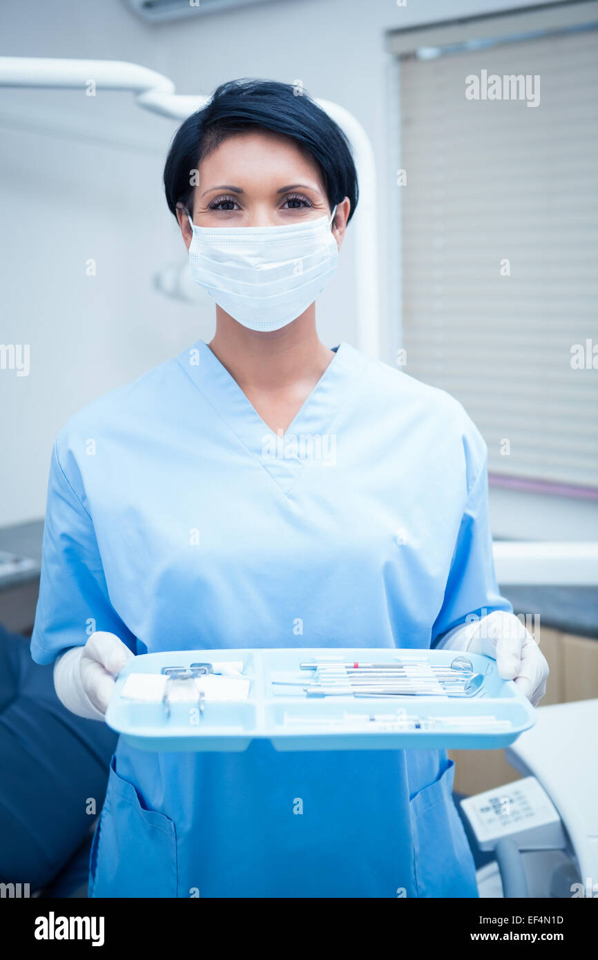 Female dentist in blue scrubs holding tray of tools Stock Photo Alamy