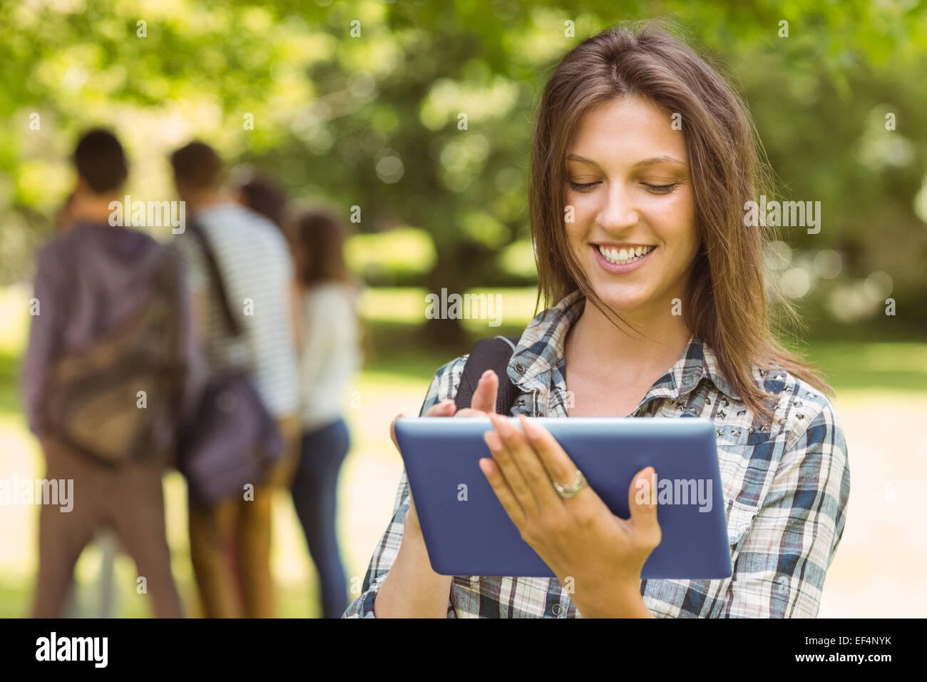 Portrait of a smiling student with a shoulder bag and using tablet ...