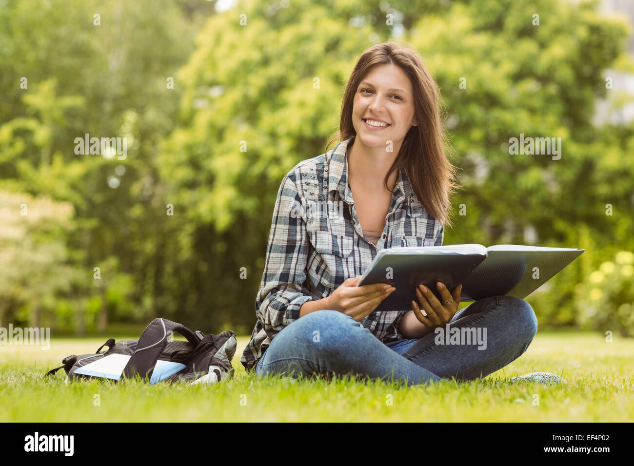 Smiling student sitting and holding a book Stock Photo - Alamy