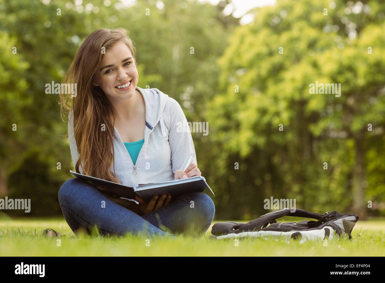 Smiling student sitting and holding book Stock Photo - Alamy