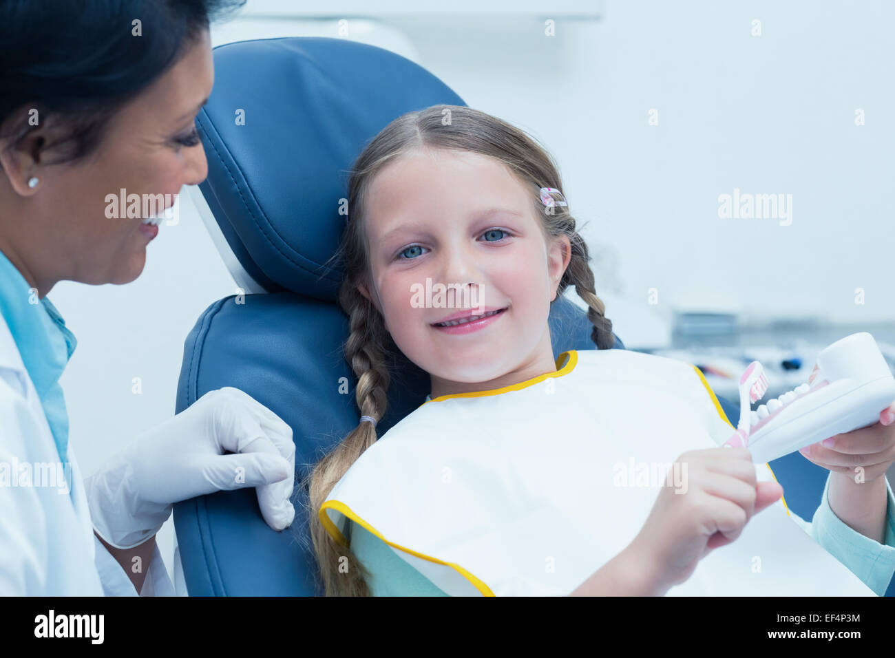 Female dentist teaching girl how to brush teeth Stock Photo Alamy
