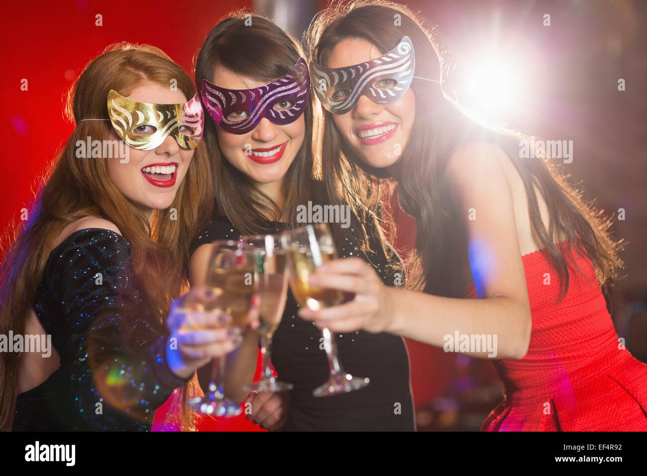 Friends in masquerade masks toasting with champagne Stock Photo
