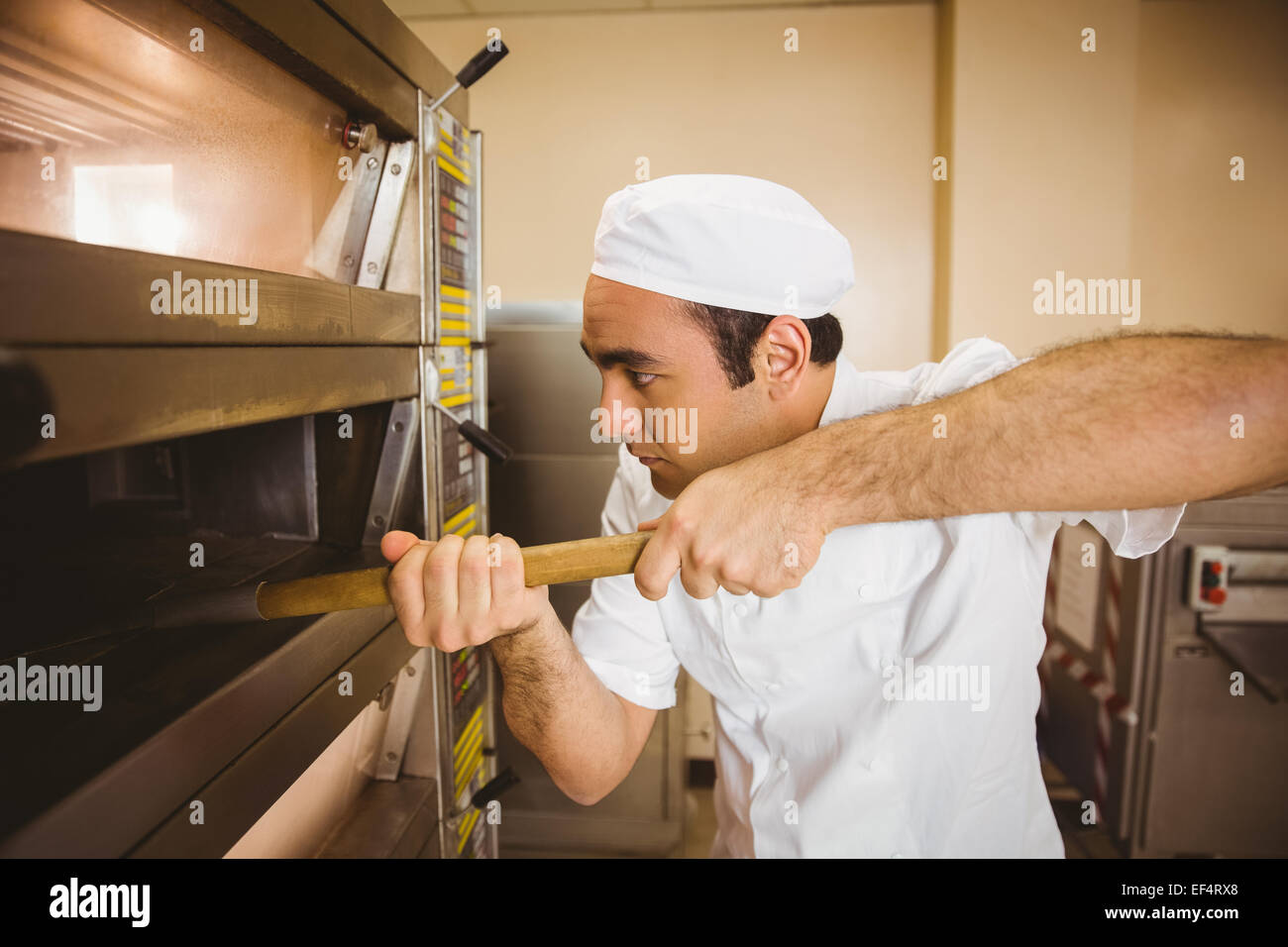 Baker taking bread out of oven Stock Photo
