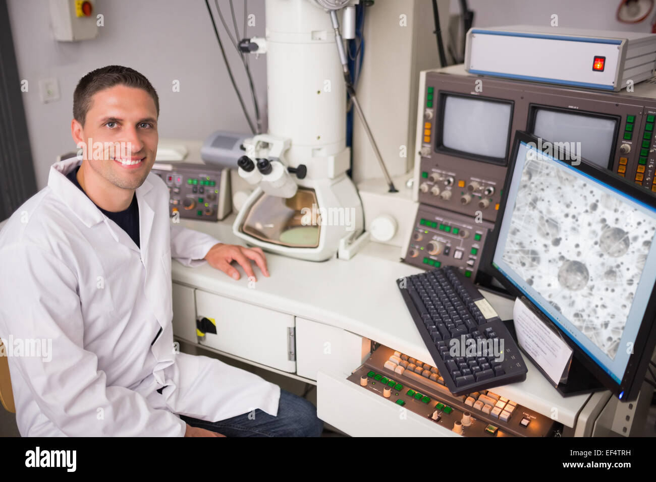 Biochemistry student using large microscope and computer Stock Photo
