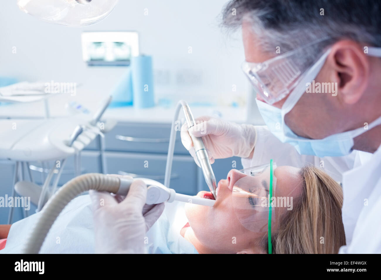 Dentist examining his patient with a suction hose Stock Photo Alamy