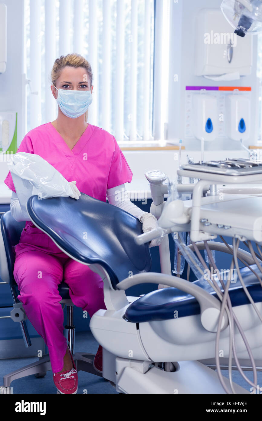 Dentist in pink scrubs looking at camera beside chair Stock Photo Alamy