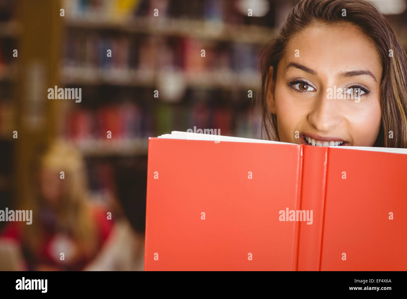 Pretty brunette student holding book in front of her face Stock Photo ...