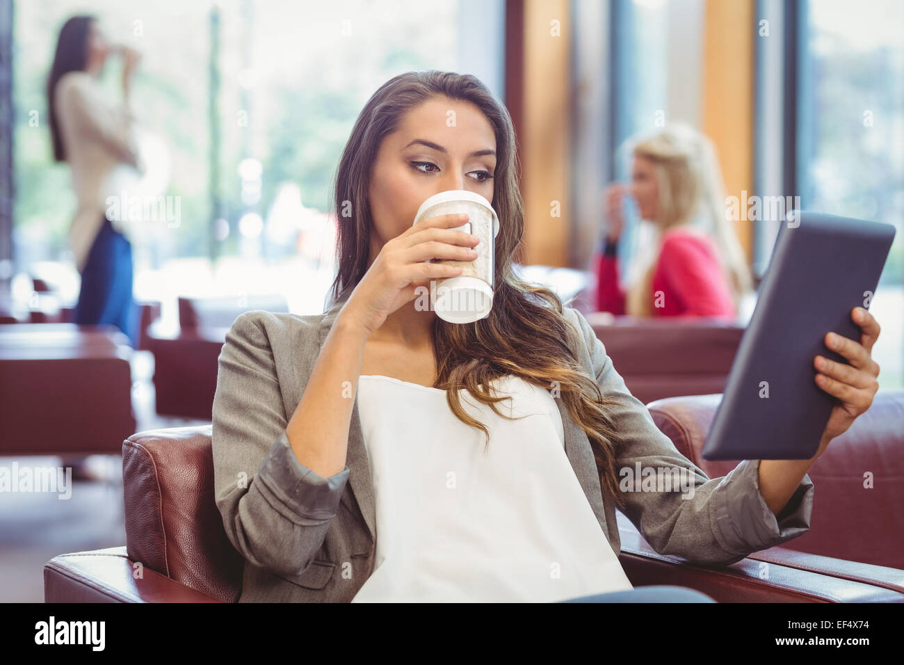 Student using digital tablet and holding disposable cup Stock Photo