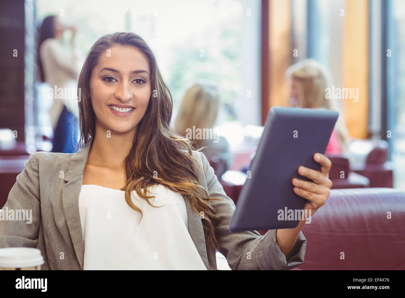 Student using digital tablet and holding disposable cup Stock Photo