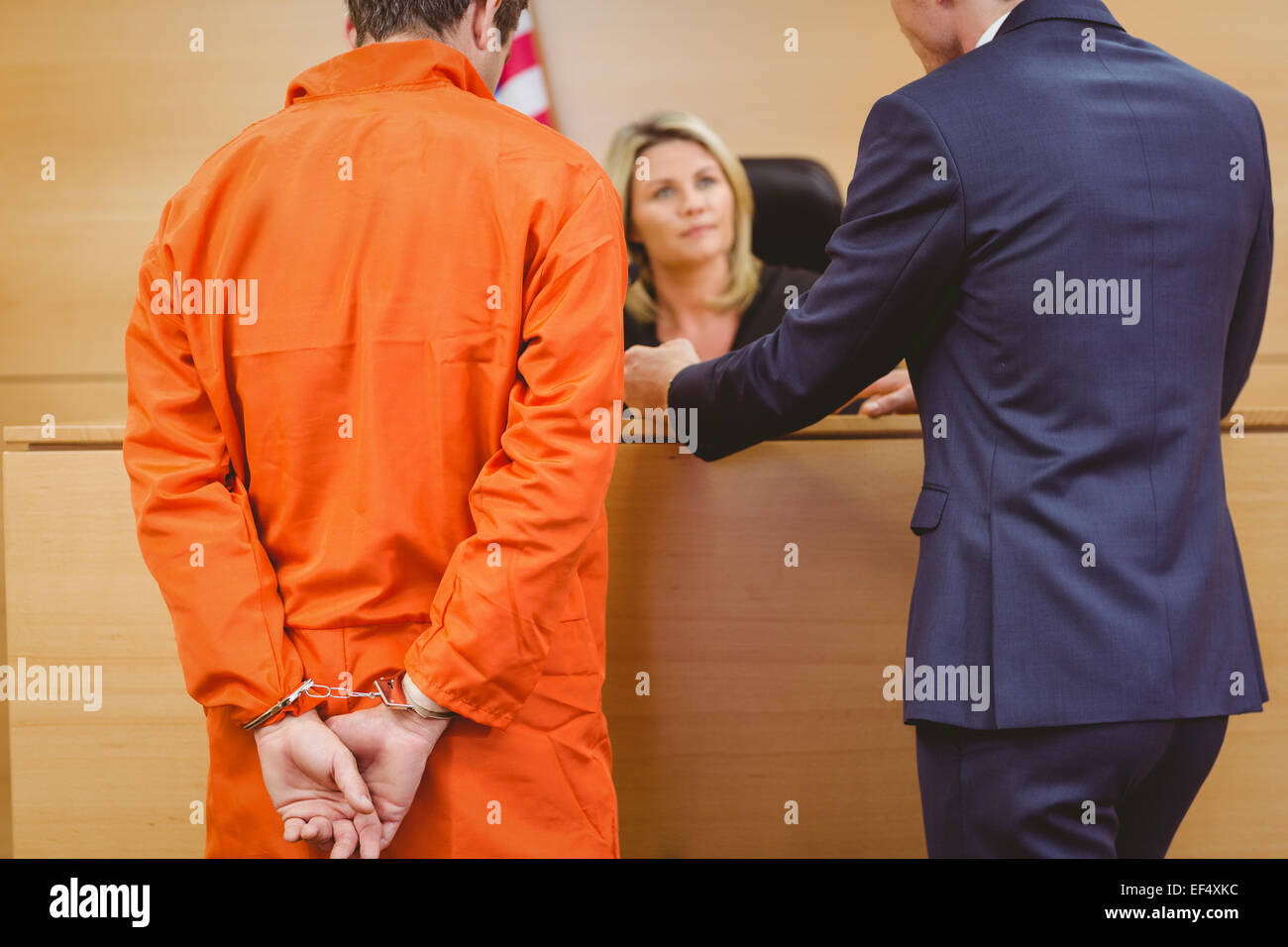 Lawyer and judge speaking next to the criminal in handcuffs Stock Photo