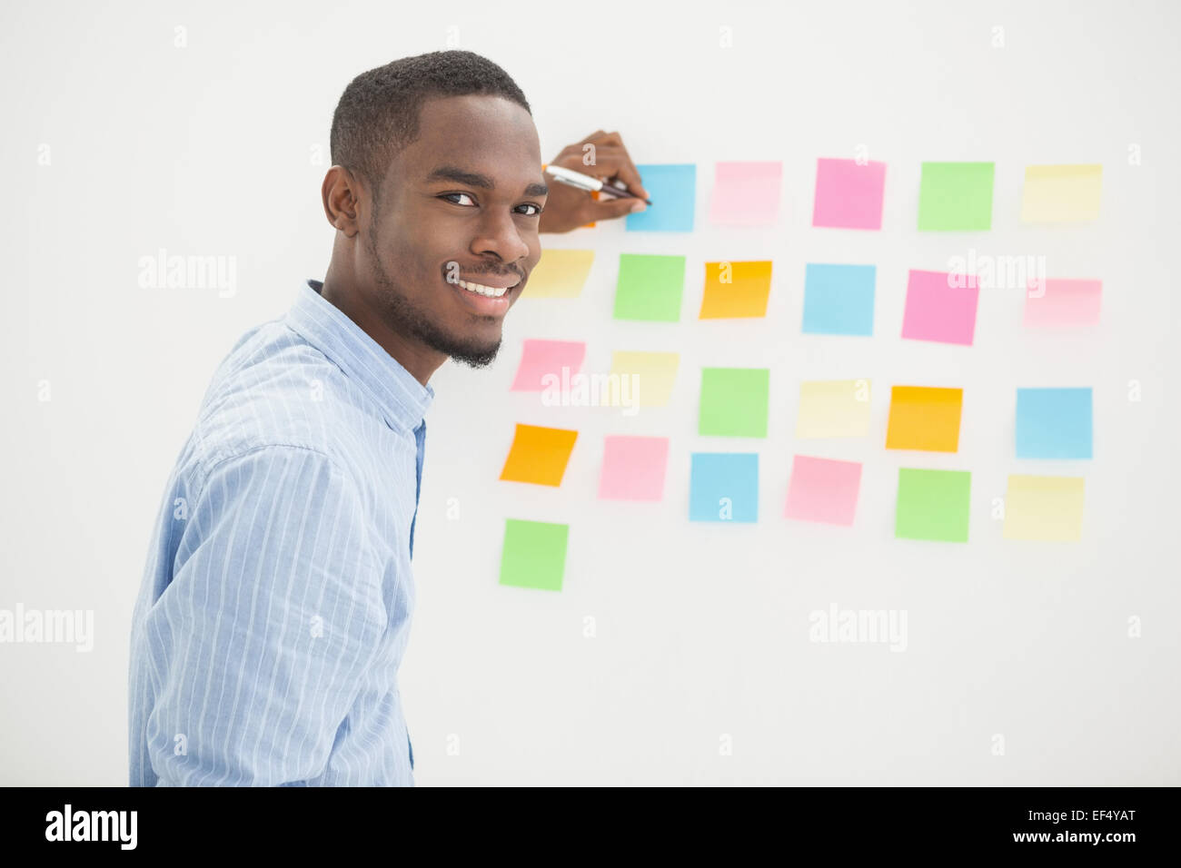 Smiling businessman writing on sticky notes Stock Photo - Alamy