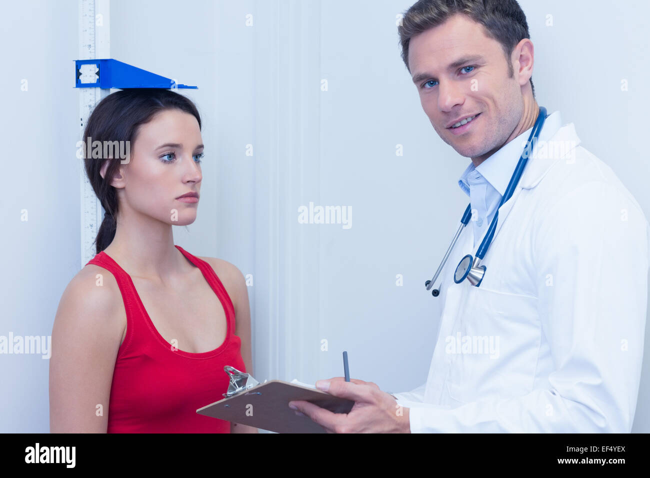 Smiling doctor standing in front of a serious patient Stock Photo