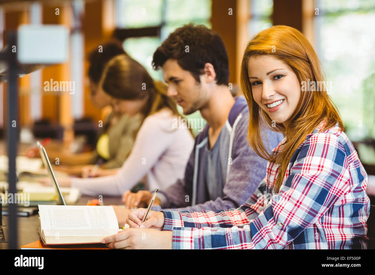 Student looking at camera while studying with classmates Stock Photo ...